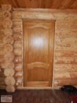 Дверь из массива сосны ДГ 7 орех в деревянном срубе фото